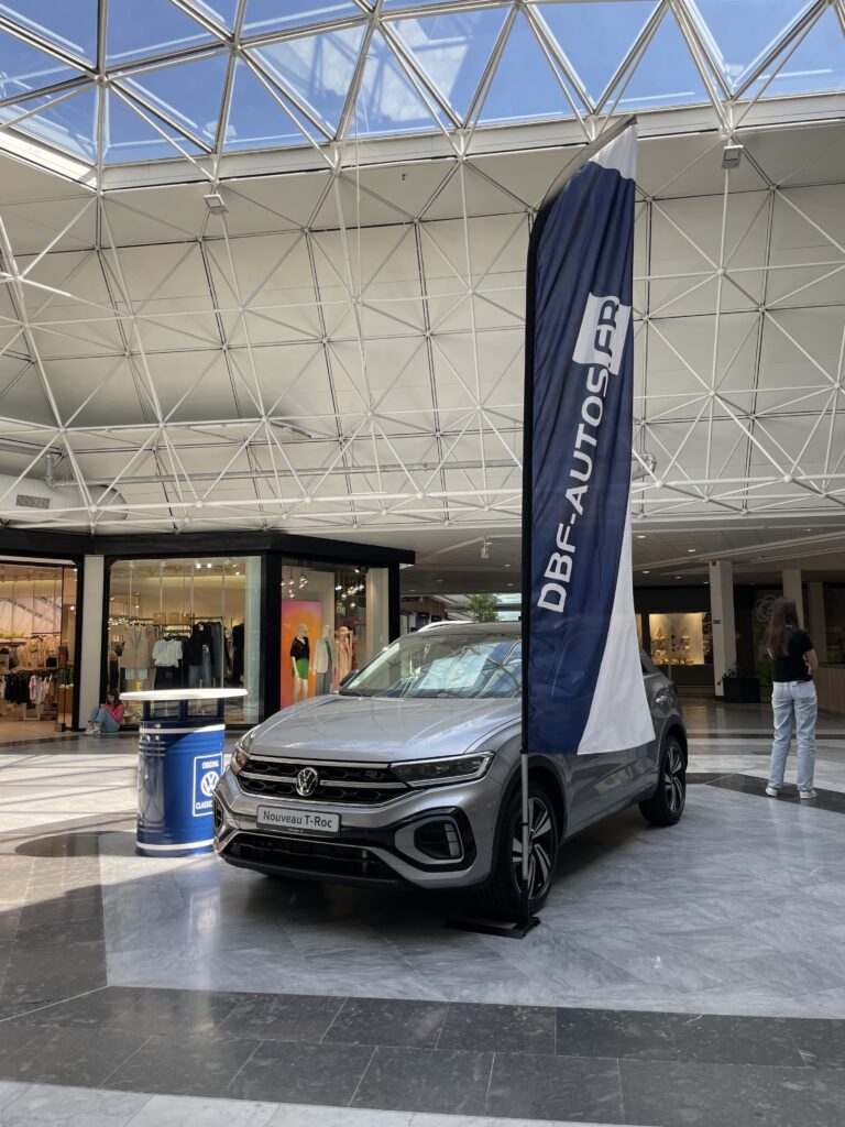 Le T-Roc exposé au milieu de l'allée centrale du centre commerciale avec des la signalétique au couleur de la marque 